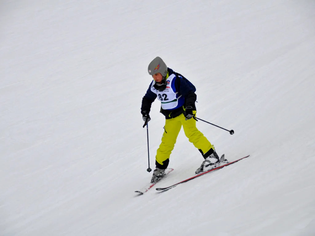 Skifahrer in gelber Hose zieht einen Schwung.